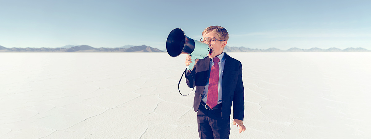 A professional man in a suit and tie confidently holds a megaphone, representing effective marketing strategies by Viabrand agency.
